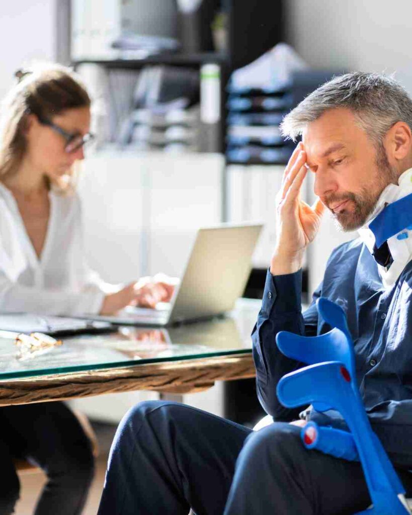 Man with a worried expression holding his head in an office setting.