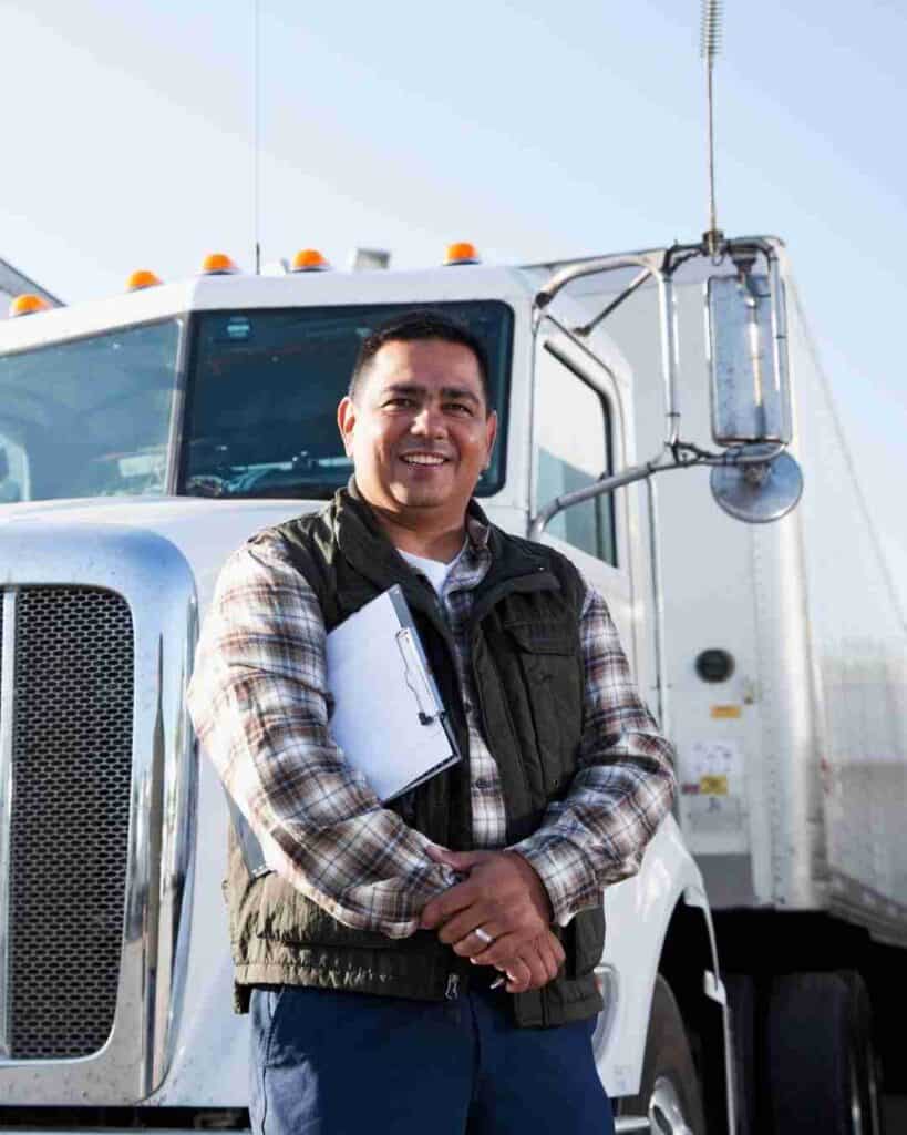 Smiling man with clipboard in front of a large truck in Texas.